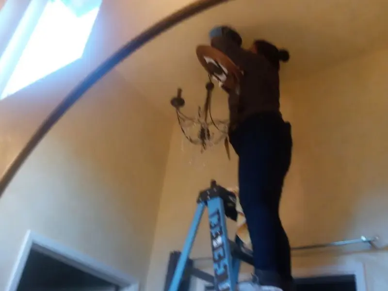 Electrician installing a chandelier in a Osceola residence